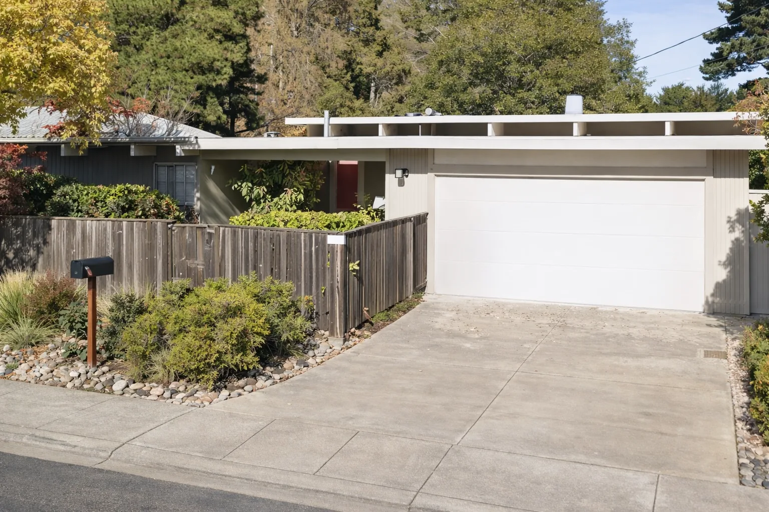 AI-generated illustration of a cream Eichler with a deep flat-roof overhang on exposed beams, a weathered board fence, and a single wide garage door.