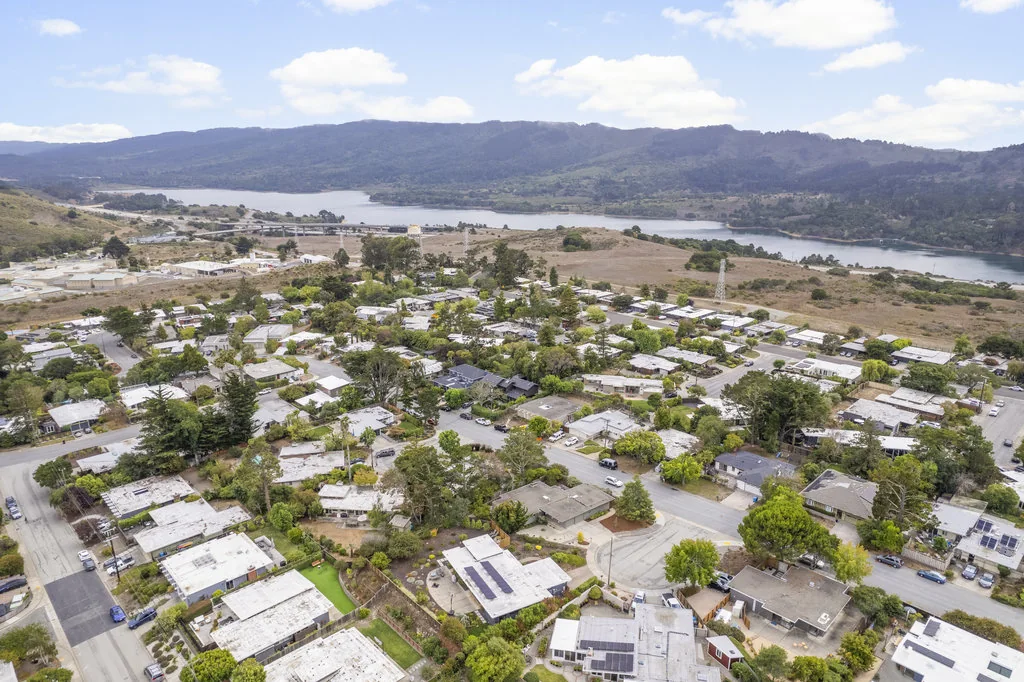 Wide aerial of the San Mateo Highlands showing hundreds of flat-roofed Eichler houses laid out along the ridge.