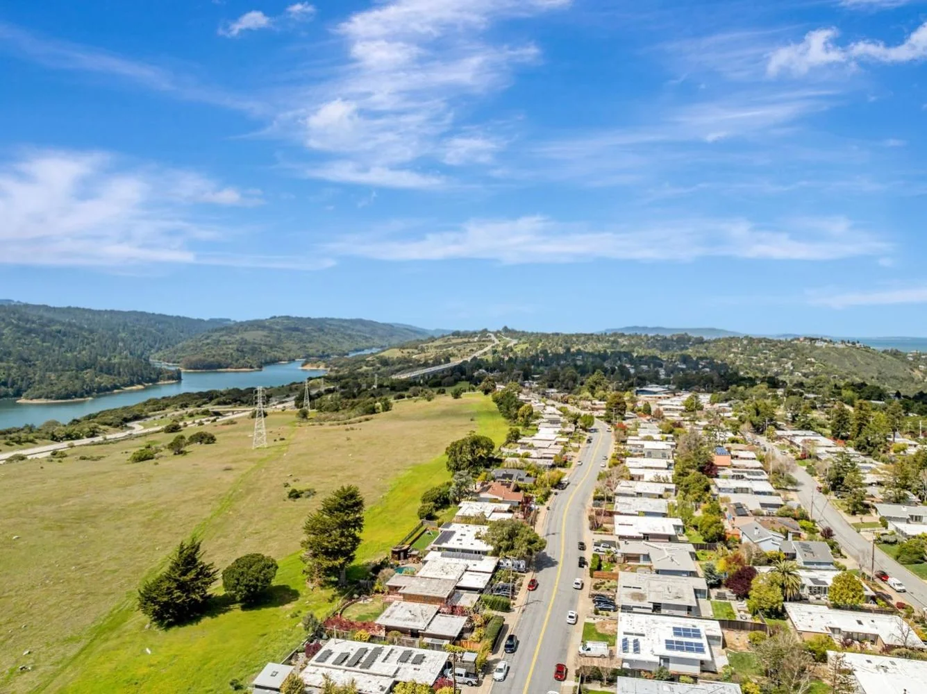 An aerial along Lexington Avenue showing Eichlers lining one side of the road and open watershed grassland on the other, running down to Crystal Springs Reservoir.
